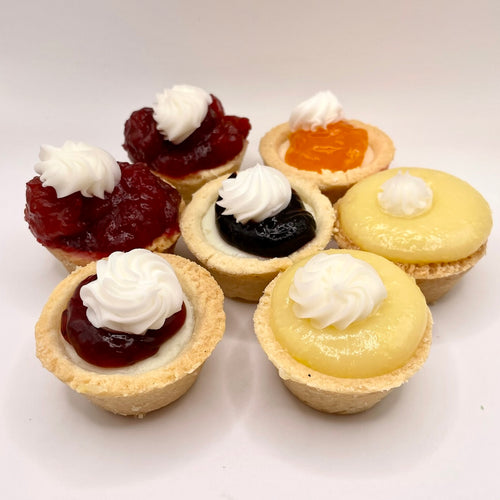 Assorted mini tarts with different fillings on a white background