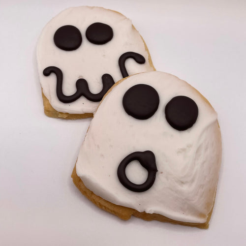Two ghost-shaped cookies with white icing on a white background
